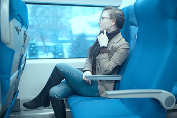 girl sits on a train / winter transport, one adult girl sits by the train window traveling