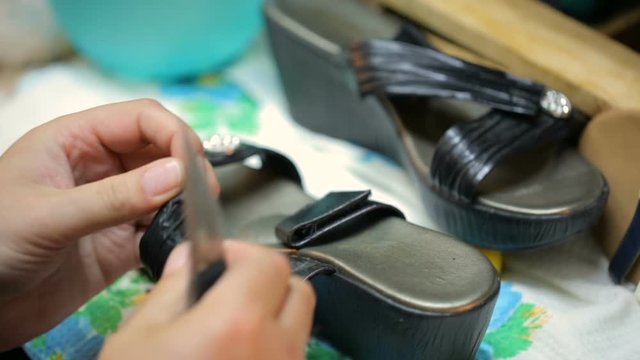 Shoemaker repairing female shoe. Close shot.