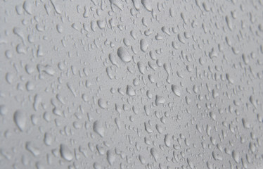 Small raindrops on a silver metal surface, a little side view, the sharpness zone of the flu is visible.