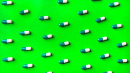 Pattern of white and green pills on a green background.
