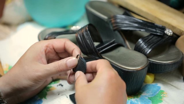 Shoemaker repairing female shoe. Close shot.