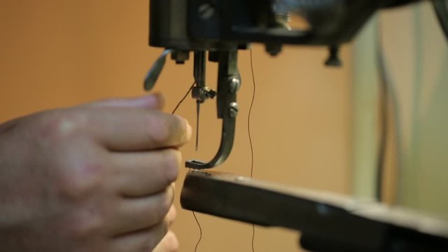 Shoemaker preparing sewing-machine. Close shot.