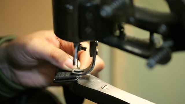 Shoemaker sewing on a sewing-machine. Close shot.