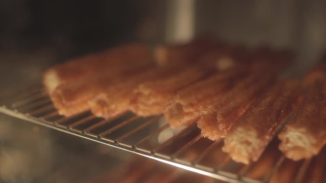 Cinnamon churros through glass on a rack