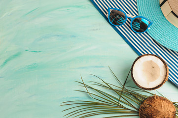 Summer composition or layout. Tropical palm leaves, hat, glasses, beach towel, coconut on a background of sea greens. The concept of the summer season and heat. Flat lay, top view, copy space