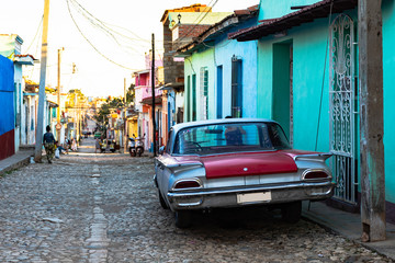 classic car on cobblestone road in front of colorful houses in trinidad, cuba