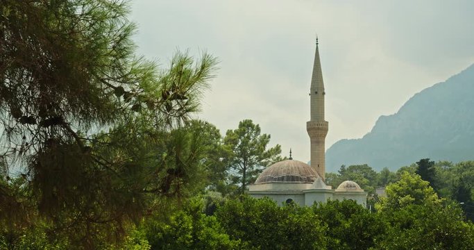 A small mosque in a provincial town among the gardens against the backdrop of the mountains.