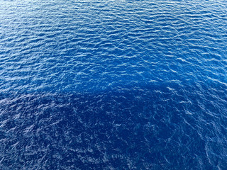 Sea background. Close-up texture of blue water. Ripple of blue sea water. Textured ocean water background. Cropped shot, horizontal, free space. Rest and travel concept.