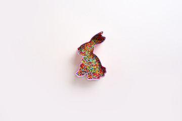 Easter festive background. Bunny shape cookie cutters with multicolored confectionery topping. Minimal modern style.