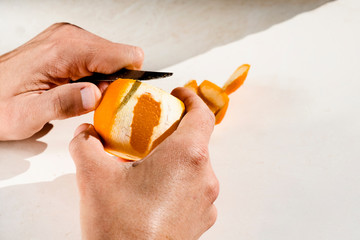 man peeling an orange with a knife