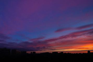 Colorful cloudy epic sky on sunrise, over the panoramic silhouette of the buildings. Moscow city skyline, morning urban landscape.