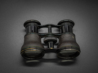 Antique opera glasses isolated on dark background. Black small vintage binocular.