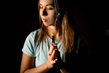 Woman practicing yoga in a studio room hold hands in namaste holding a palo santo