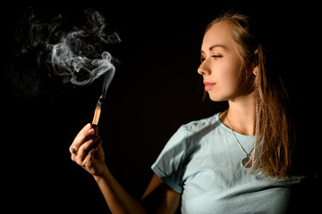 Obraz premium Girl practicing yoga in a studio room holding a smoldering palo santo in hands