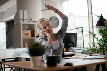 Portrait of businesswoman in office. Beautiful woman listening music at work.