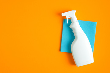 Cleaning spray bottle on blue sanitary napkin over orange background. Flat lay, top view. House...