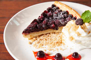 Sliced blueberry pie with fresh whipped cream and cookie crumble