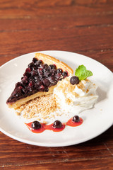 Sliced blueberry pie with fresh whipped cream and cookie crumble