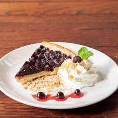 Sliced blueberry pie with fresh whipped cream and cookie crumble
