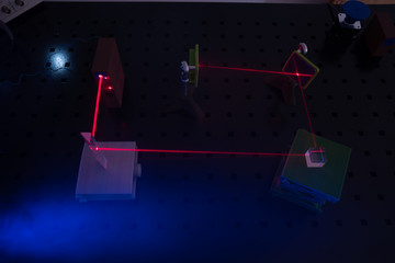 Experiment in optic lab with laser device. Red laser on optical table in physics laboratory