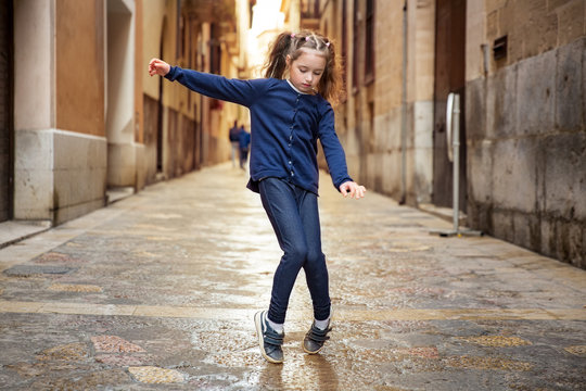 Cute little girl dancing on city street. Narrow streets of Palma de Mallorca old town. 