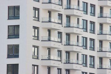 Parts of the modern facade of apartment buildings made of glass and concrete with highlights on the windows in beige colors. Trends in buildings