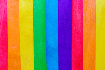 Stained wooden popsicle sticks in a rainbow of colors to make an abstract striped background