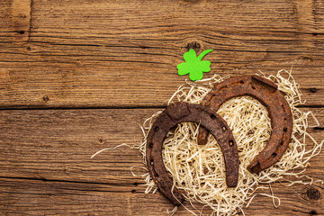 Two cast iron metal horse horseshoes with felt clove leaf on hay. Good luck symbol, St.Patrick's...