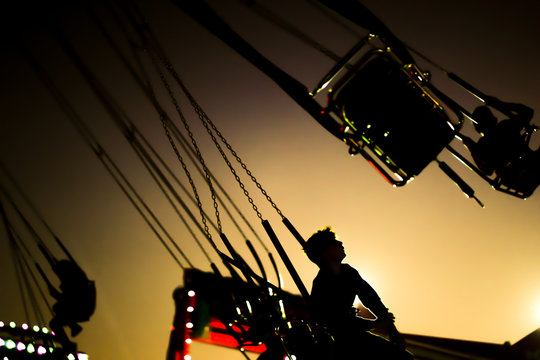 silhouette ofa young boy riding on a merry-go-round swing