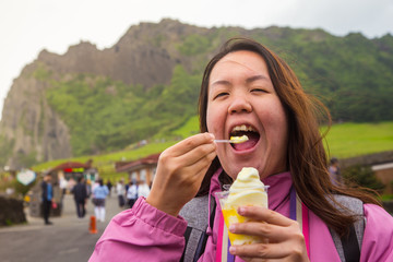 An Asia Chinese lady eat an ice cream, with background of volcanic cone in Jeju-island, Korea