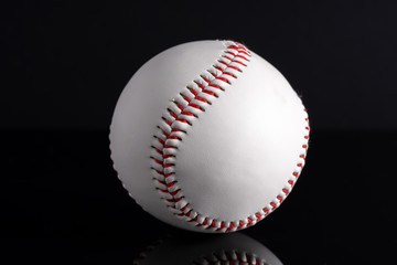 White softball and black reflection in low light view.