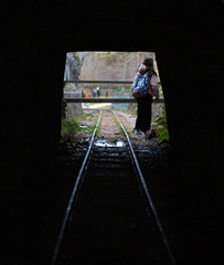 woman walking out of a cave with train tracks