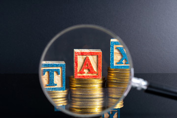 Magnifier glass and coins stacking and tax letter cube with low light view.