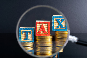 Magnifier glass and coins stacking and tax letter cube with low light view.