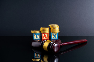 Gavel hammer and stacking coins and tax letter cube with low light view.