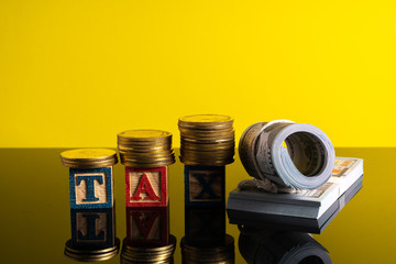 TAX letter and stacking coins with financial concept. Image in low light view.