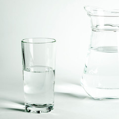 Pure clear water in a glass and jug stands on a white background