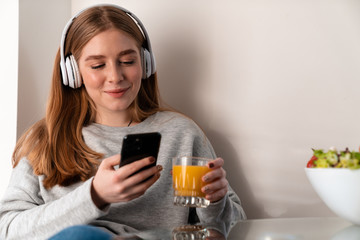Naklejka premium Positive young woman indoors at home using mobile phone.