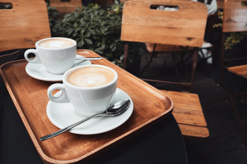 Two cups of cappuccino with latte art on wooden background.
