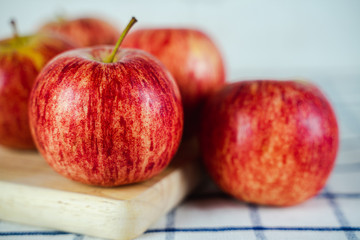 Fresh red apples on wooden cutting board and towel background.