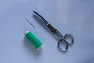 A green thread with a scissors and a needle