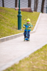Cute little boy riding a kick scooter
