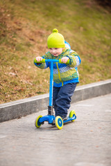 Cute little boy riding a kick scooter