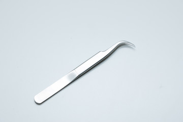 Tweezers with a curved edge on a uniform background. Eyebrow correction tool.