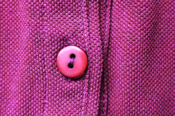 Simple button on vivid purple cloth texture background. Casual clothes button close up, bright...