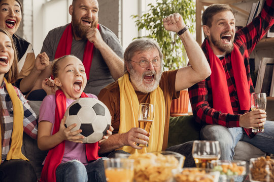 Excited, happy big family watching football, soccer match on the couch at home. Fans emotional cheering for favourite national team. Having fun from grandparent to children. Sport, TV, championship.