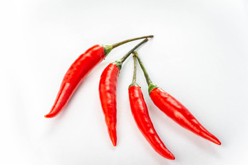 Four fresh red peppers are isolated on white background.