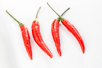 Four fresh red peppers are isolated on white background.