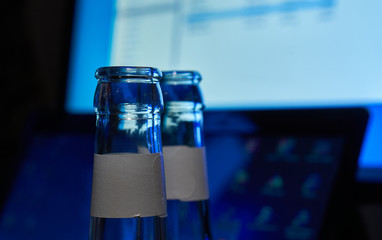 Empty beer bottles, upper part, in front of a switched on computer. Selective focus. Concept for alcohol abuse and alcohol dependency at the workplace