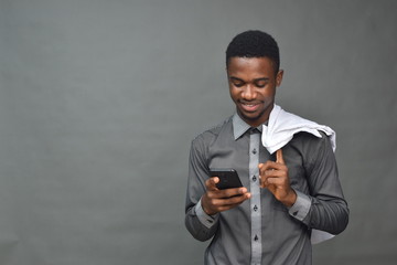 young black man in medical field, holding a white coat using a mobile phone smiling